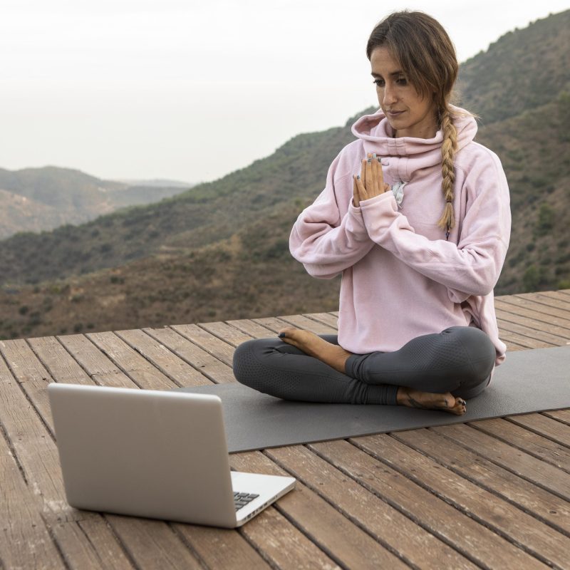 woman-doing-yoga-outdoors-with-laptop